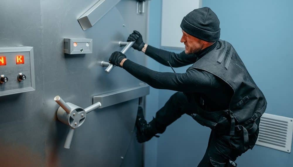 Bank robbery, male robber in black uniform trying to break vault lock. Criminal profession, theft concept